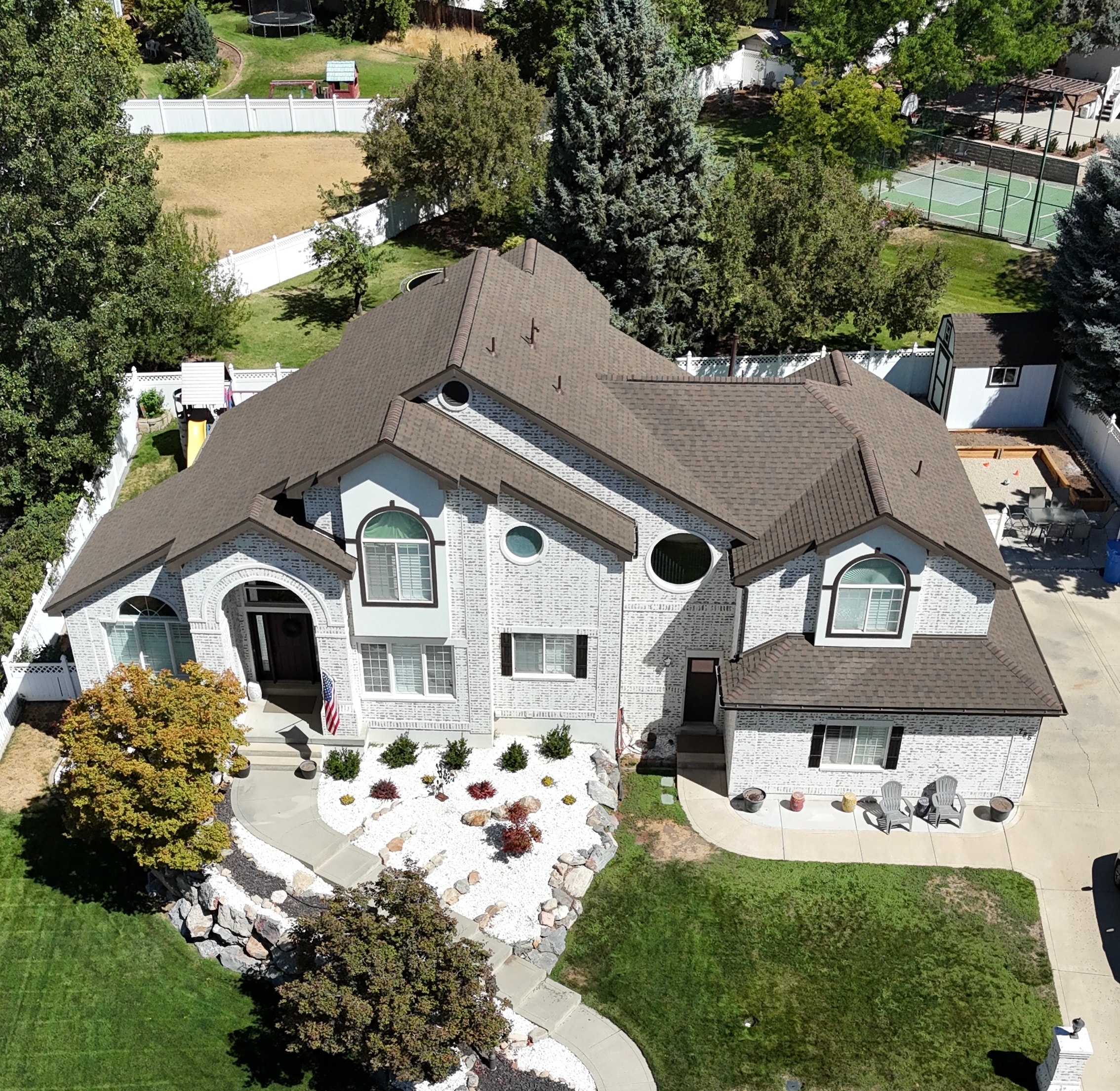 Brown architectural shingle installation on white brick home