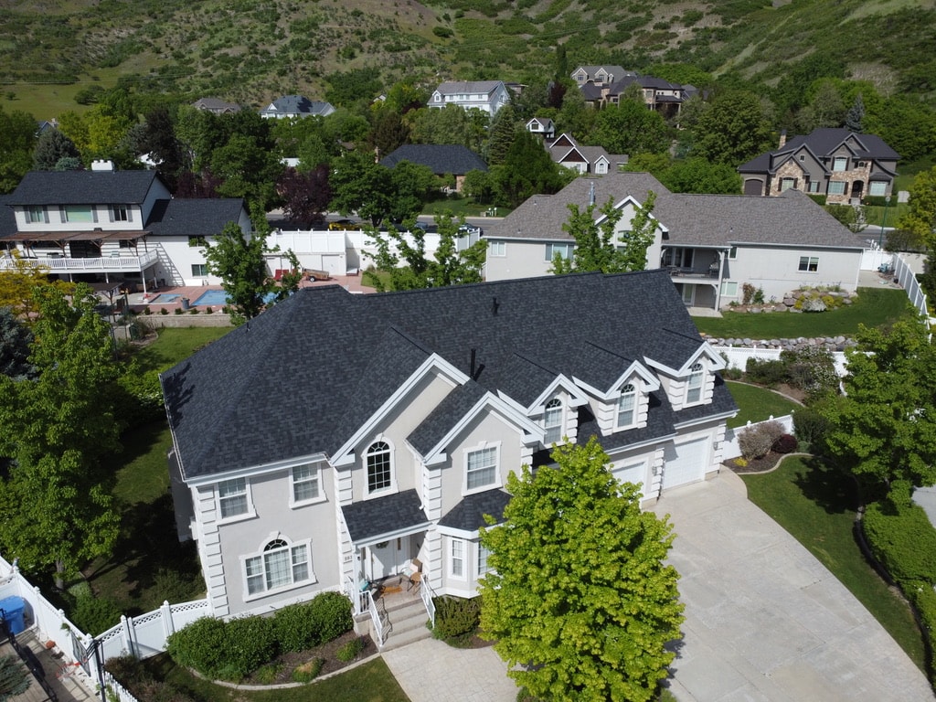Charcoal shingle roof on large white stucco home on Utah hillside